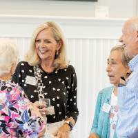 Group of four chatting at event, three women and one man